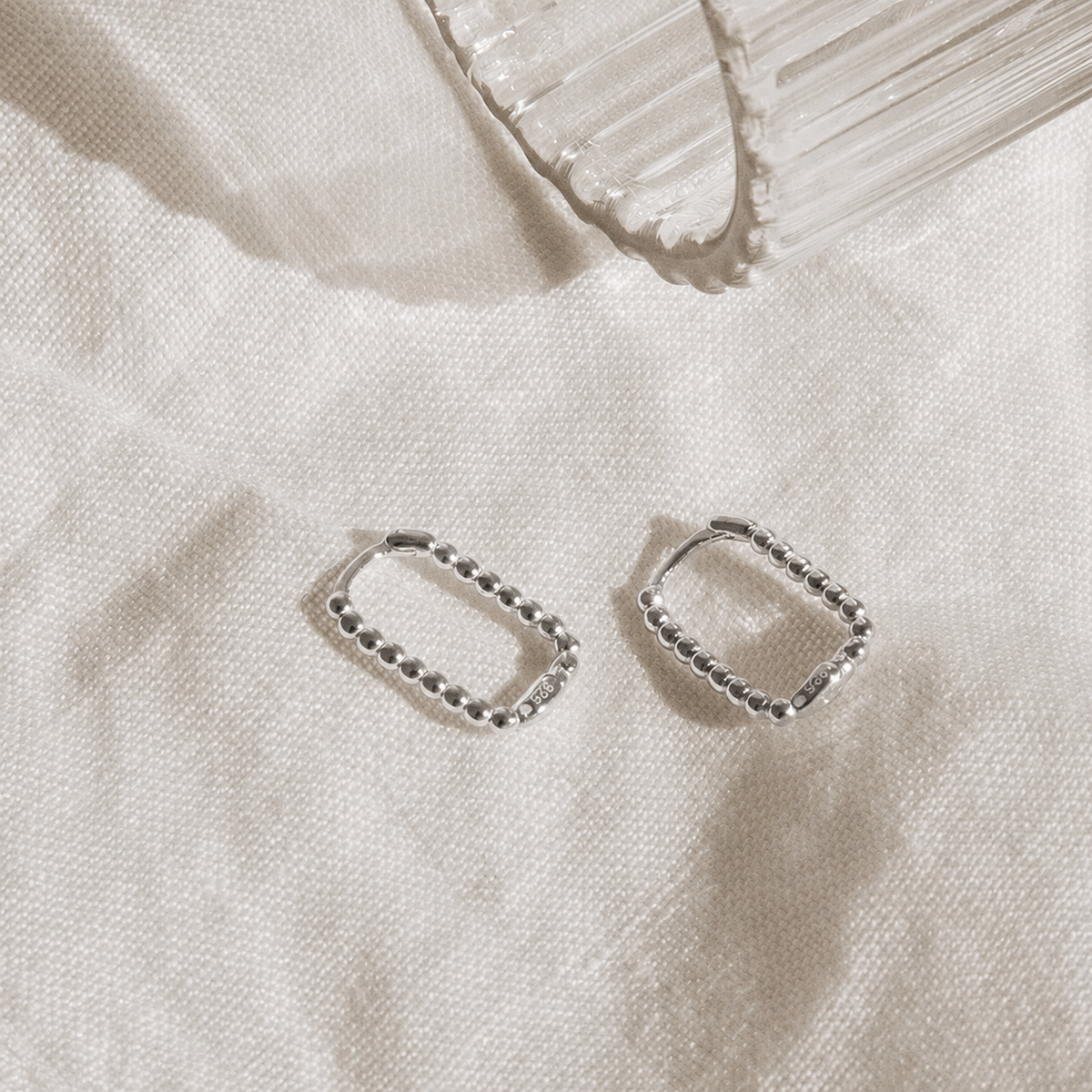 Pair of silver hoop earrings on a light fabric background