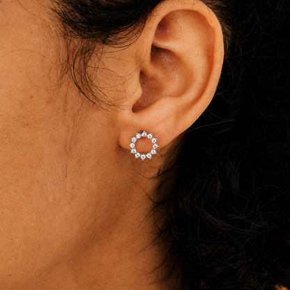 Close-up of an ear wearing a circular earring with a dark background