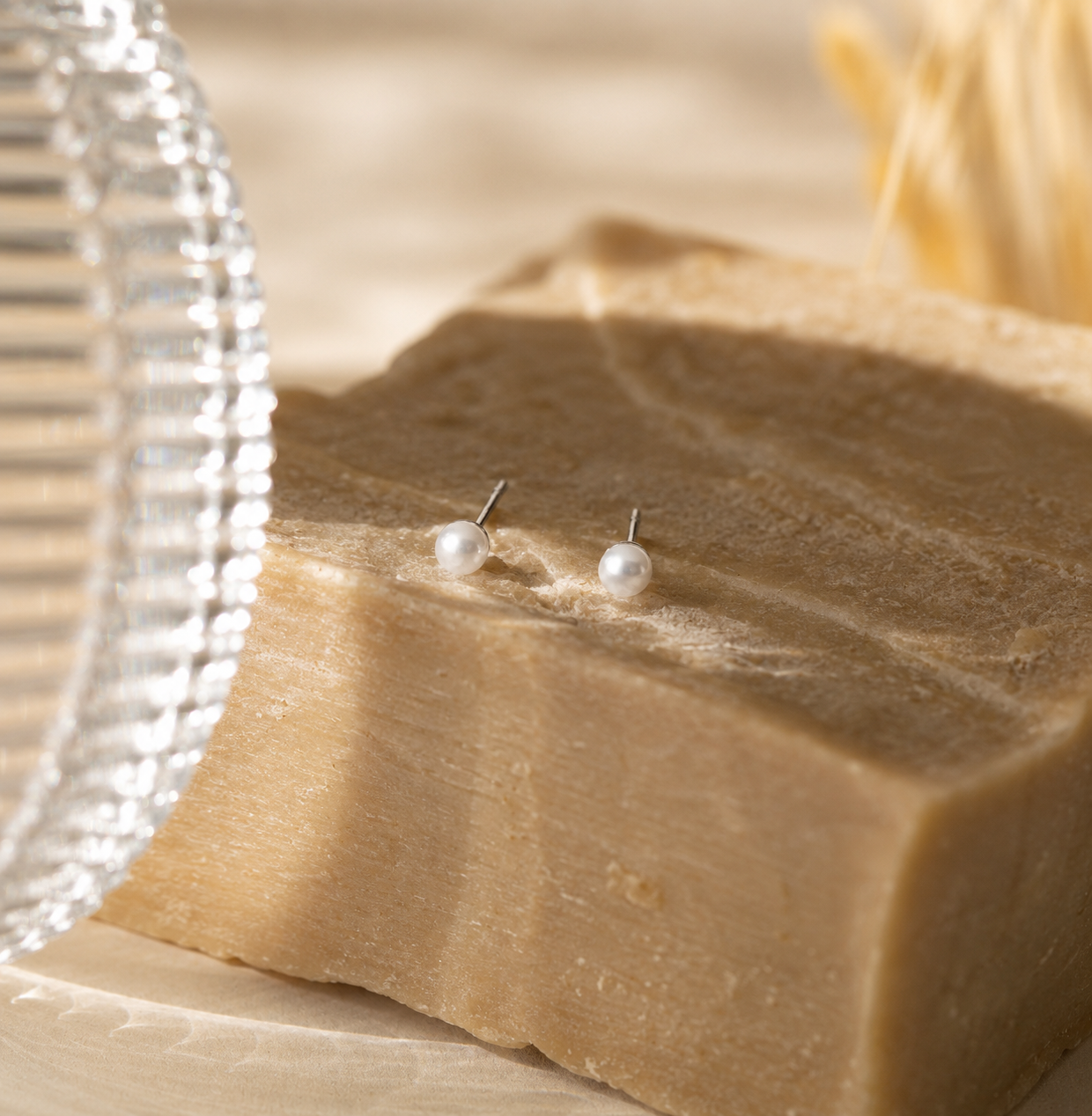 Pearl stud earrings on a block of soap with a blurred background