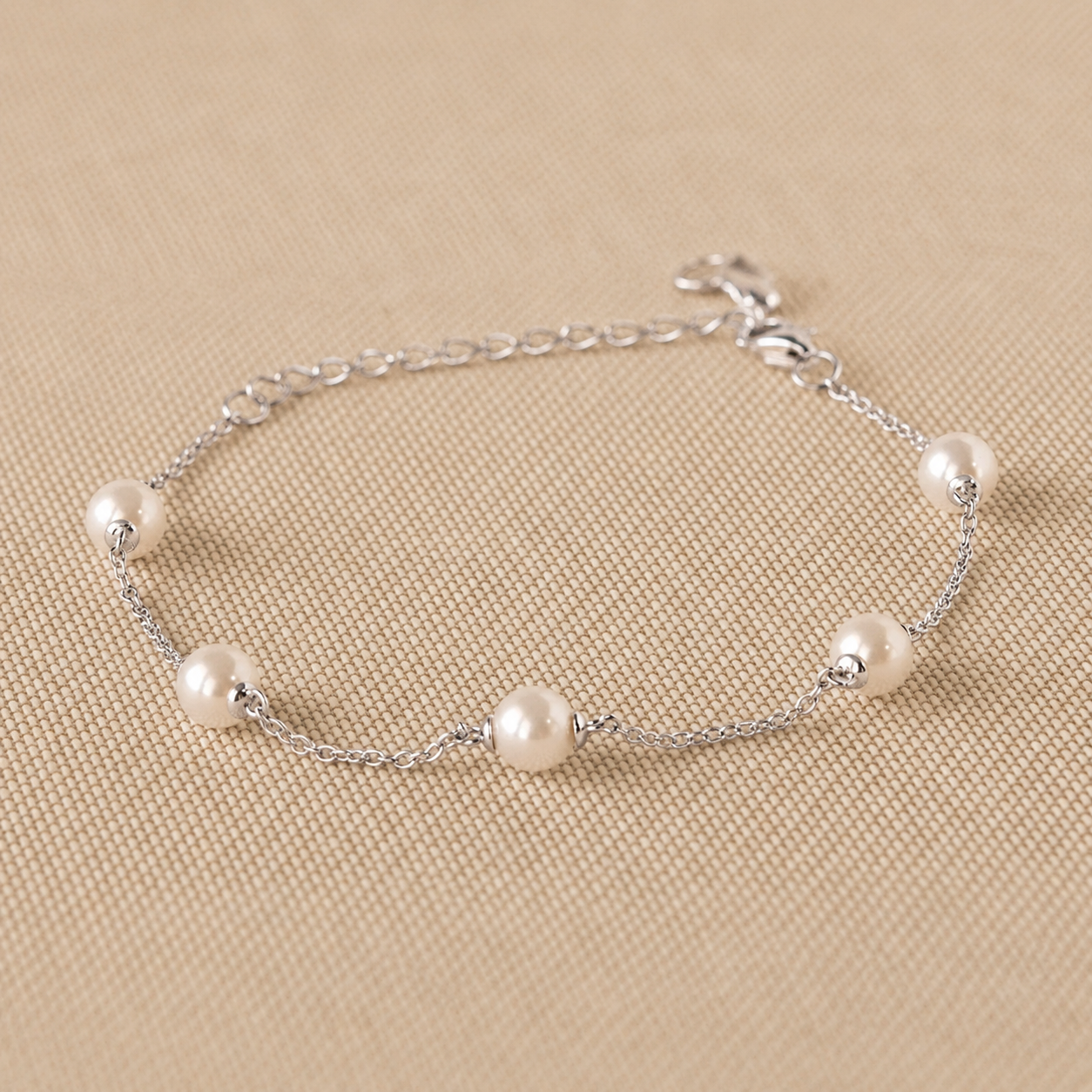 Silver bracelet with pearls on a beige background