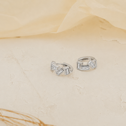Pair of silver hoop earrings on a beige surface