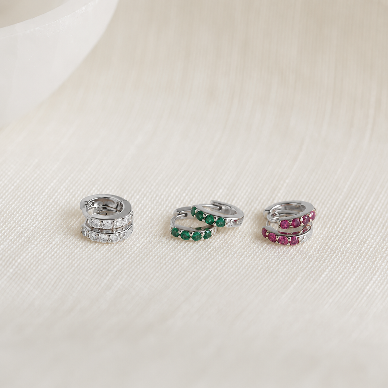 Three silver rings with gemstones on a light fabric background