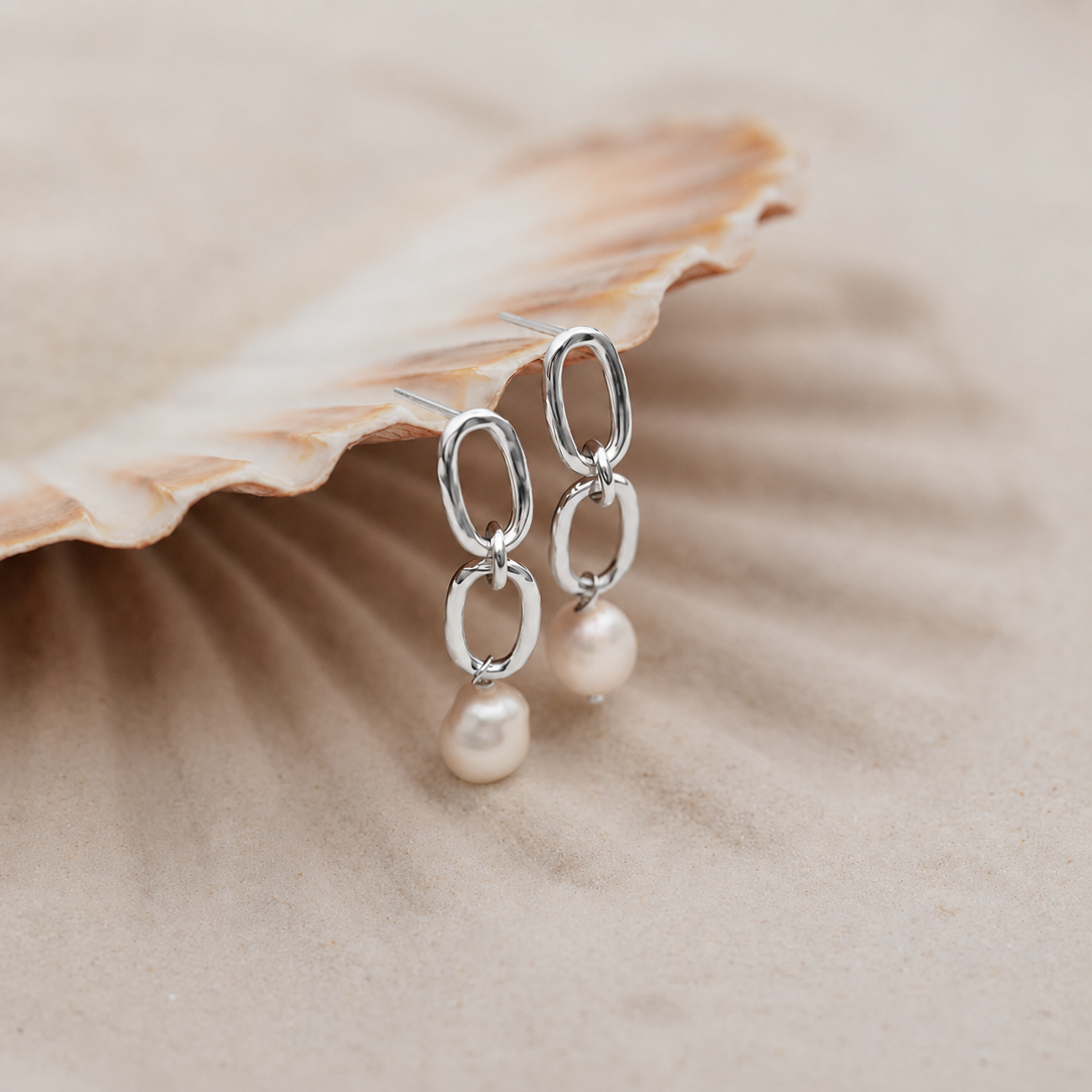 Silver earrings with pearls on a shell background