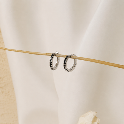 Silver hoop earrings on a mannequin arm with a neutral background