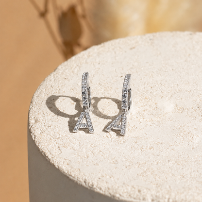 Silver earrings on a textured stone surface with a blurred background