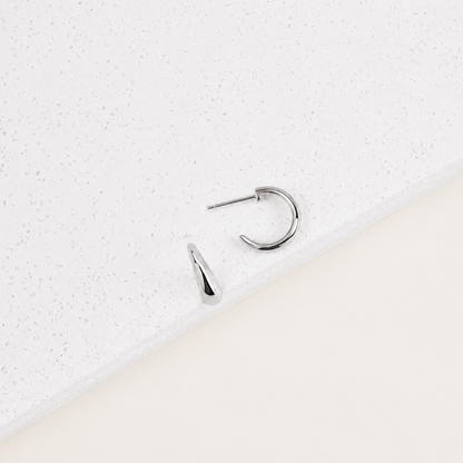 Silver hoop earring on a textured white surface