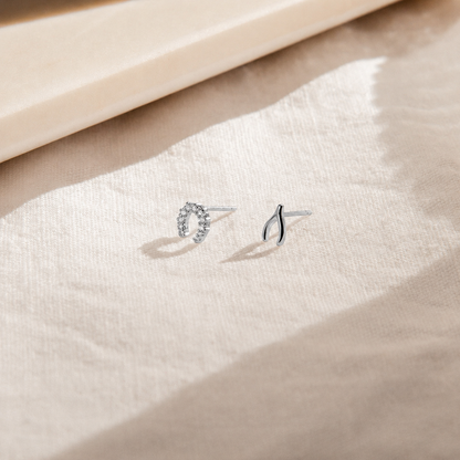 Pair of silver earrings on a soft beige fabric background