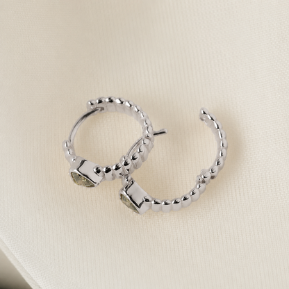 Silver hoop earrings on a beige fabric background