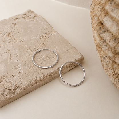 Silver hoop earrings on a stone surface with a neutral background