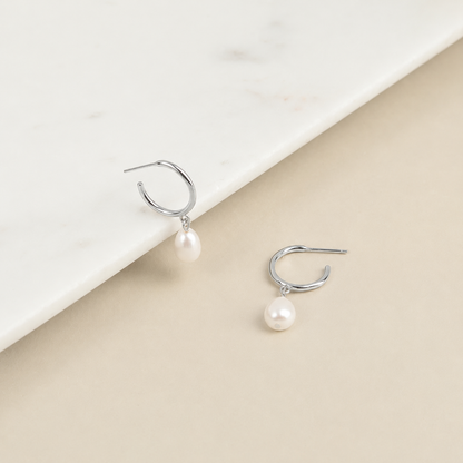 Pearl earrings on a beige and white background