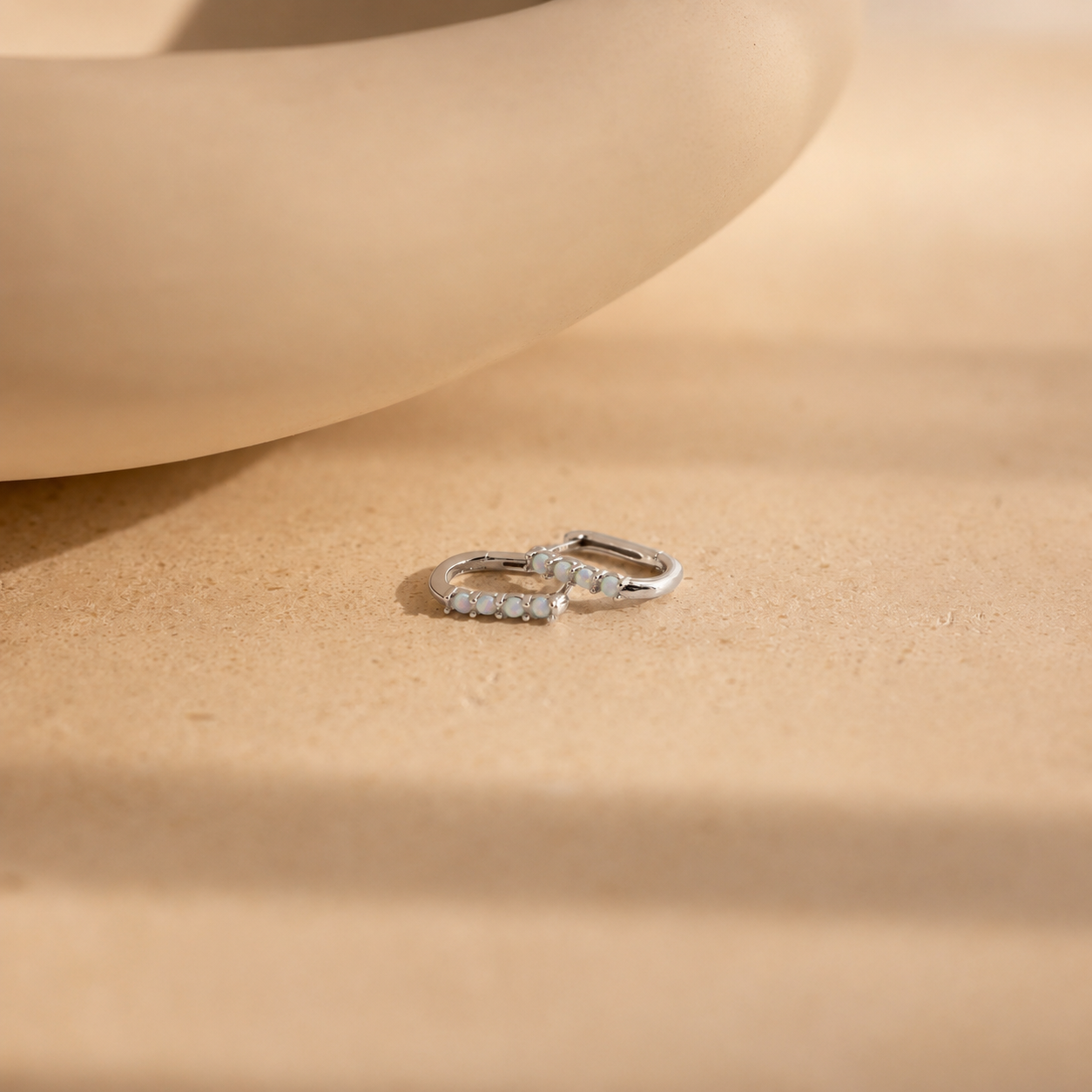 Silver hoop earrings on a beige surface