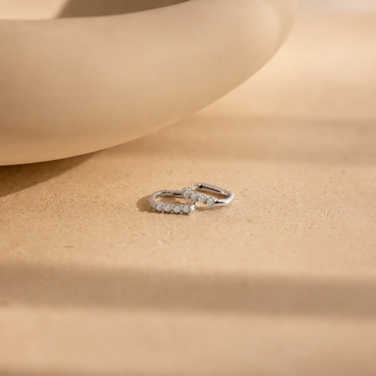 Silver hoop earrings on a beige surface