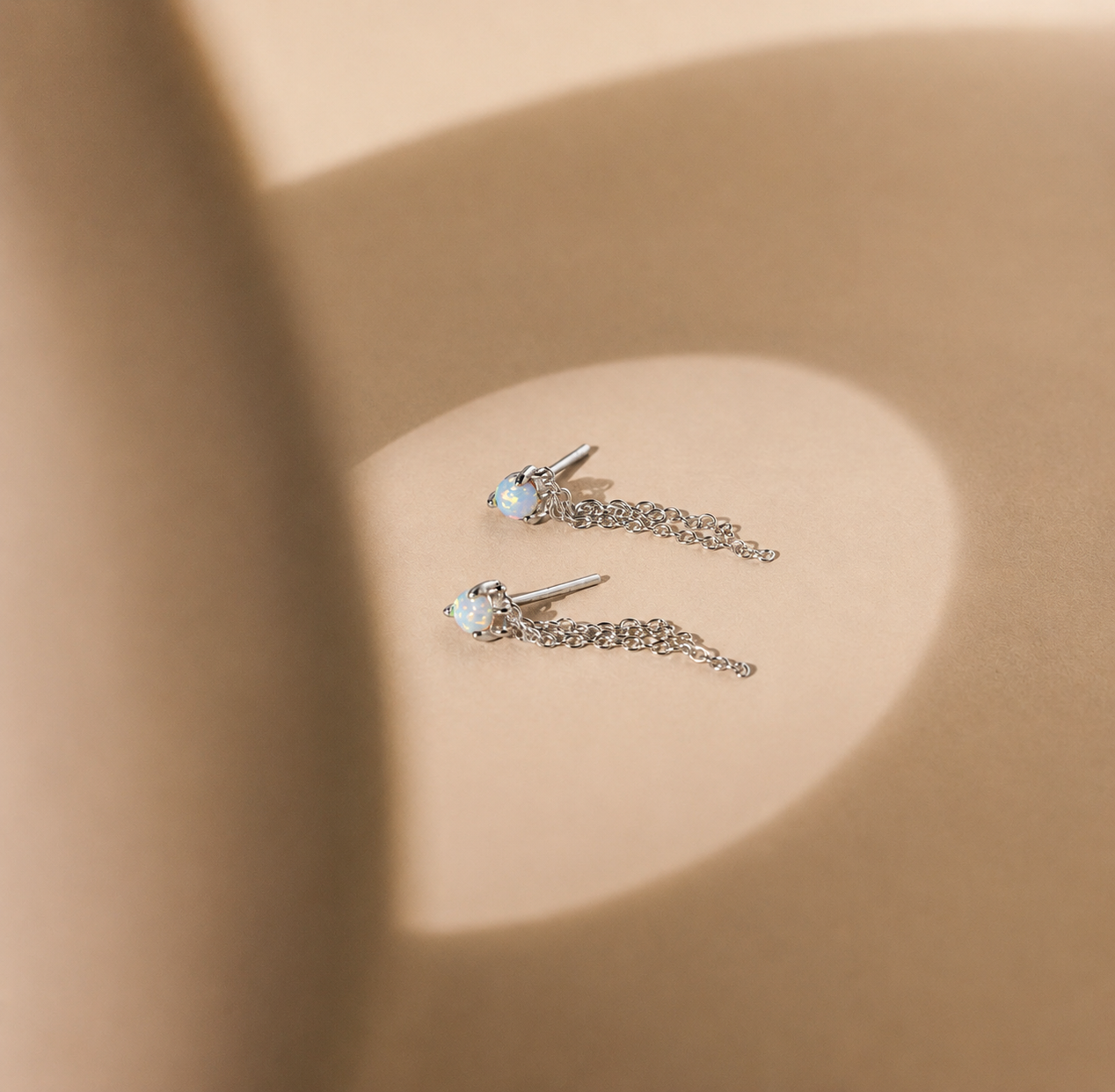 Pair of silver earrings with gemstones on a beige background
