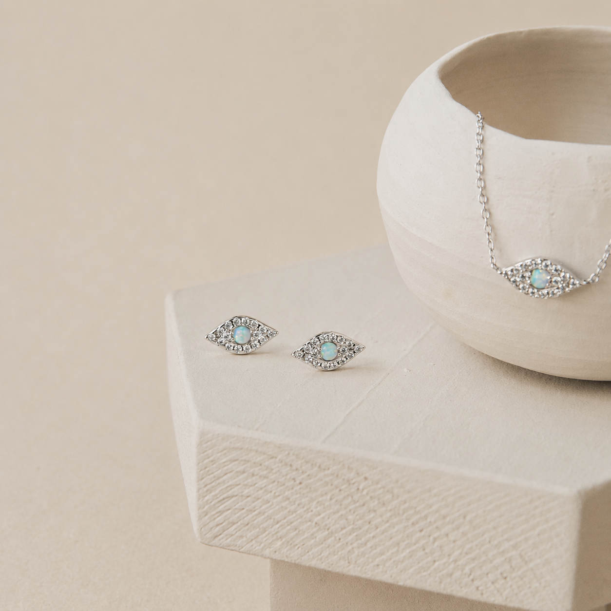 Pair of silver earrings with gemstones on a beige surface