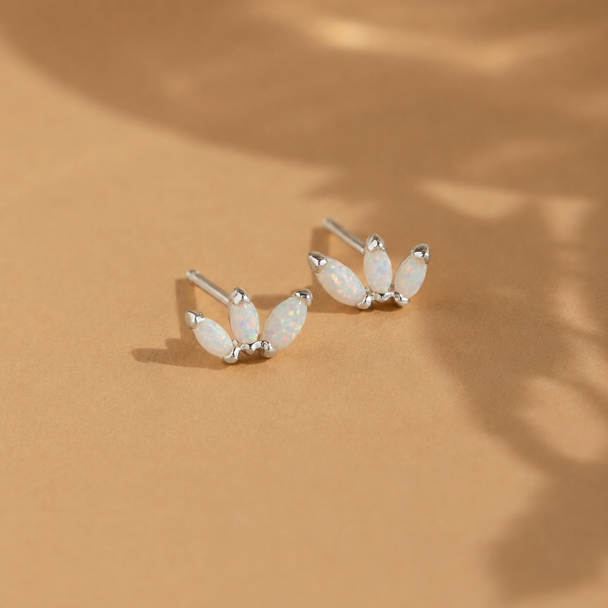 Pair of silver earrings with opal stones on a beige background