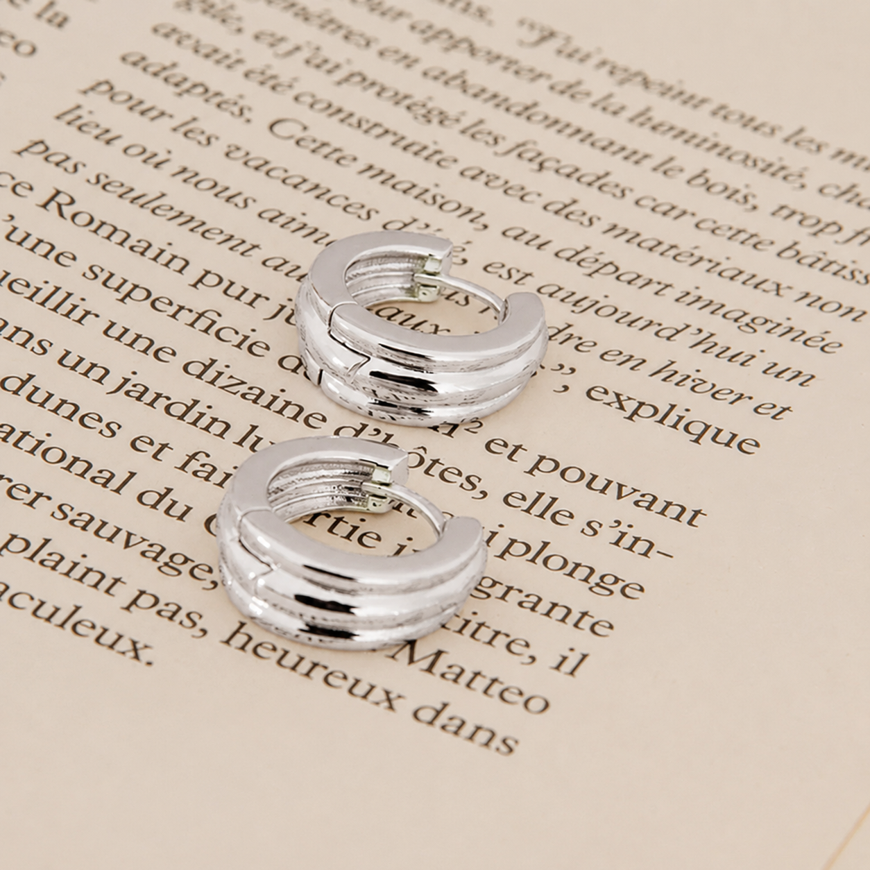 Silver hoop earrings on a piece of text