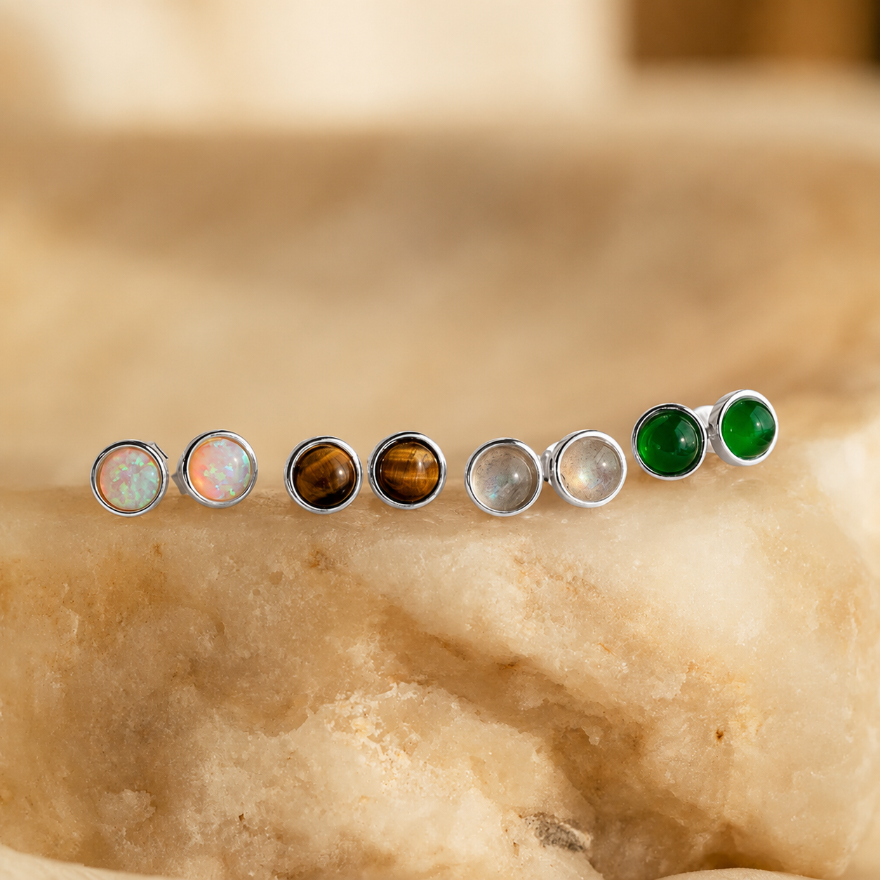 Set of gemstone stud earrings on a stone surface