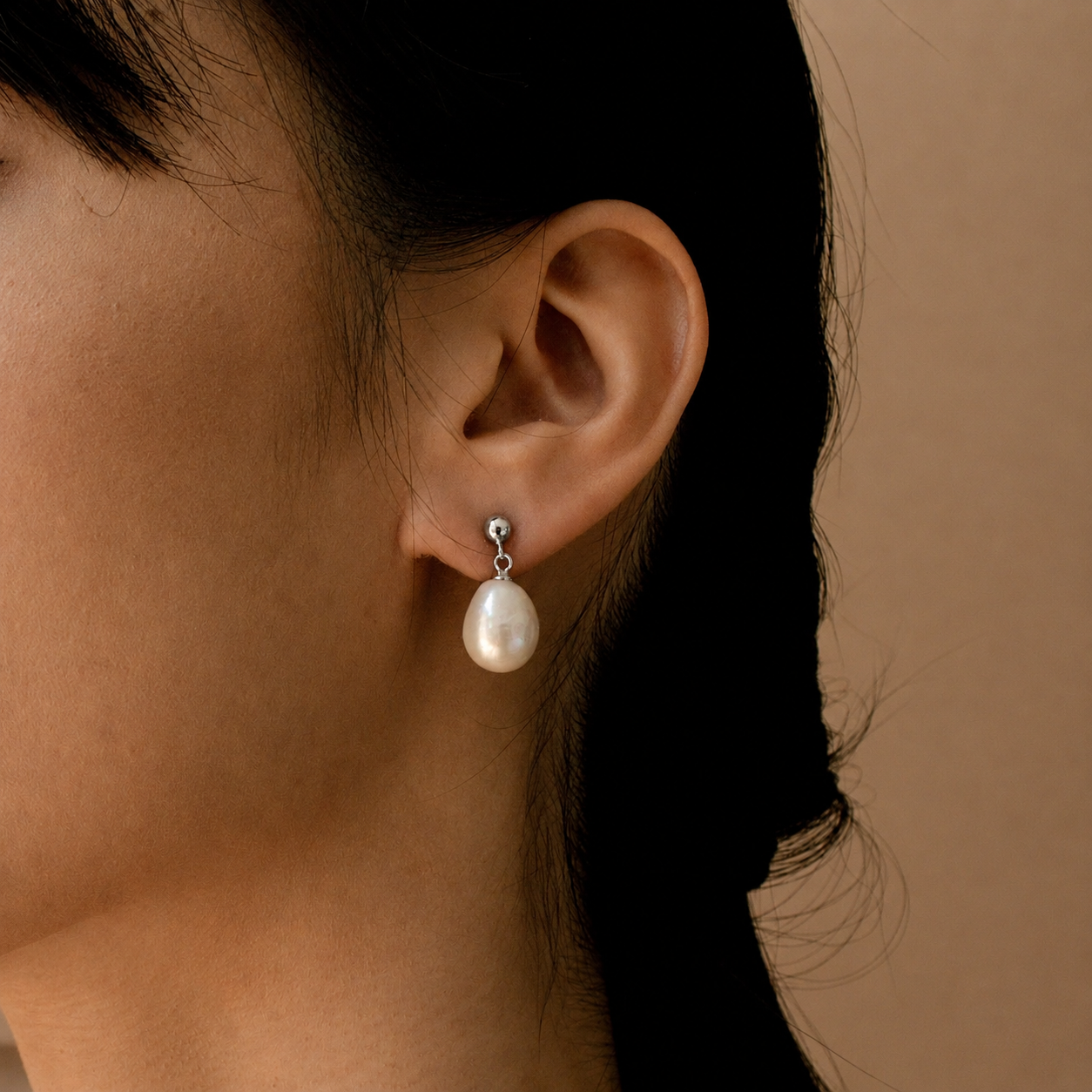 Pearl earring worn by a person with a neutral background
