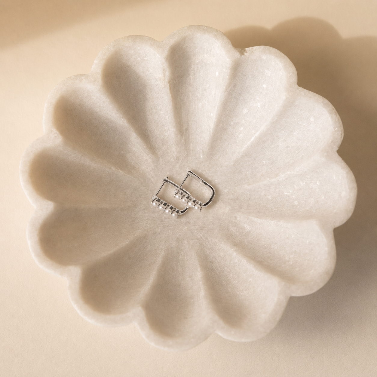 Floral-shaped white soap with a silver clasp on a beige background