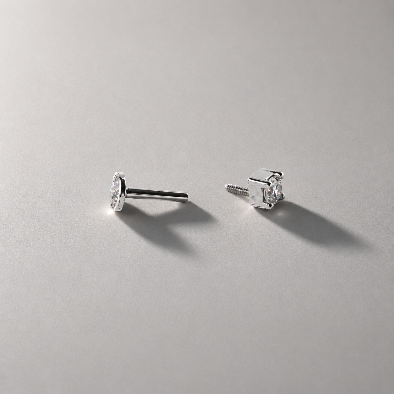Pair of silver stud earrings on a gray background