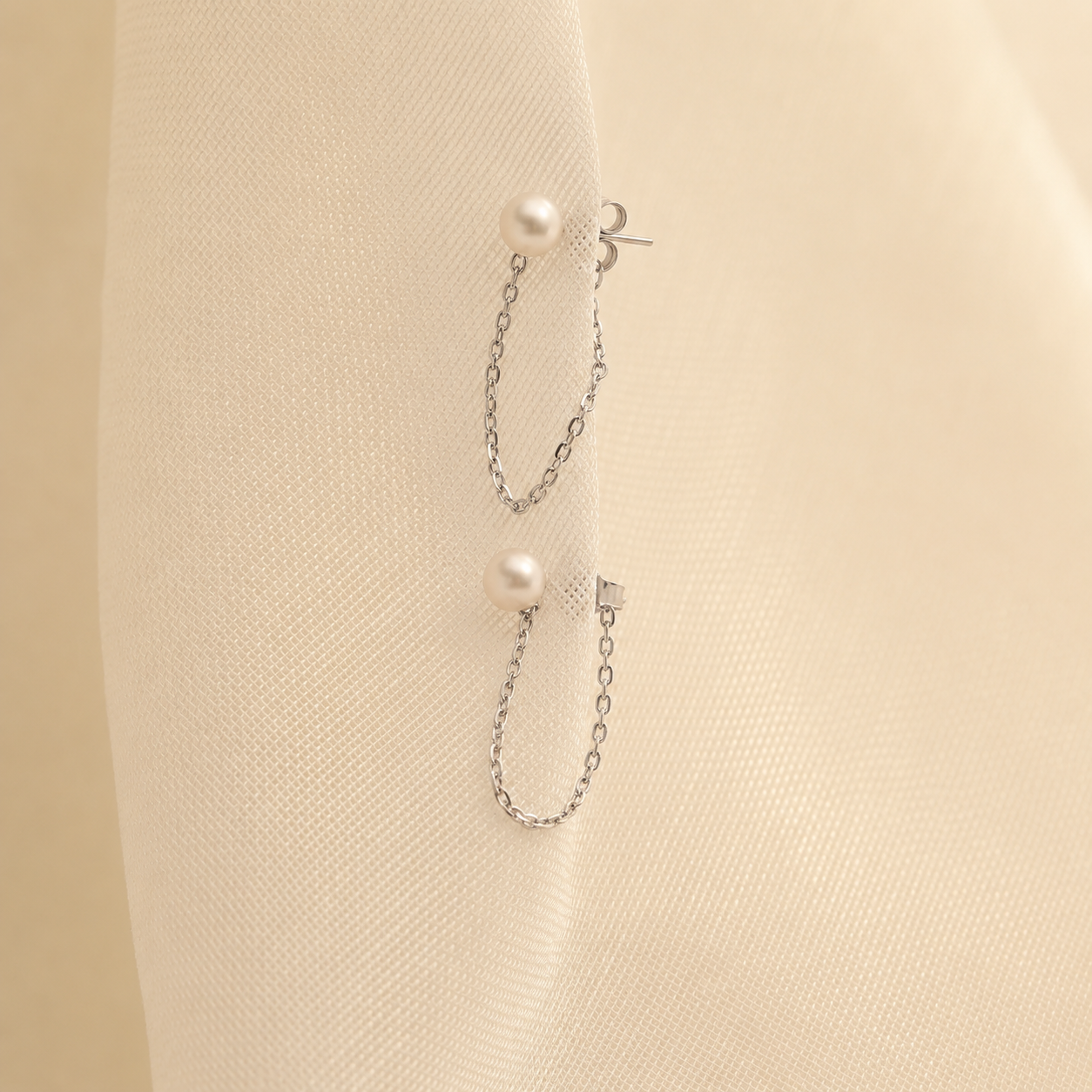 Pearl earring with chain on a beige background