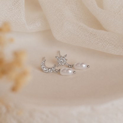 Silver earring with star and moon design on a soft beige fabric background
