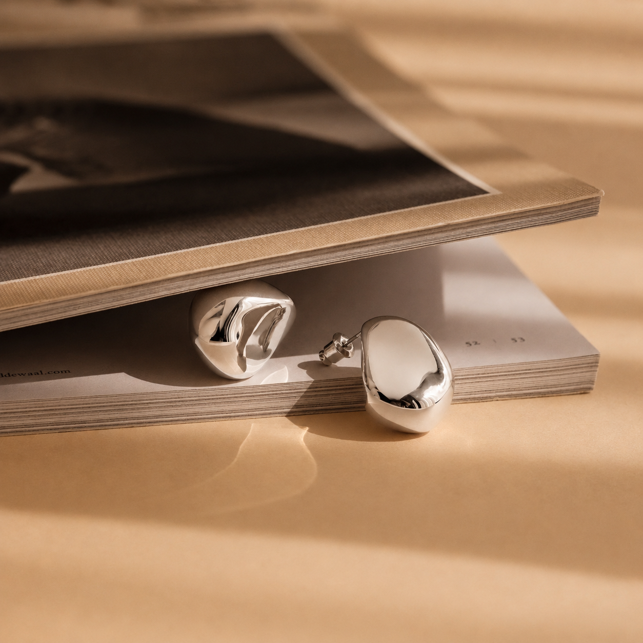 Silver earrings on a stack of books with a beige background