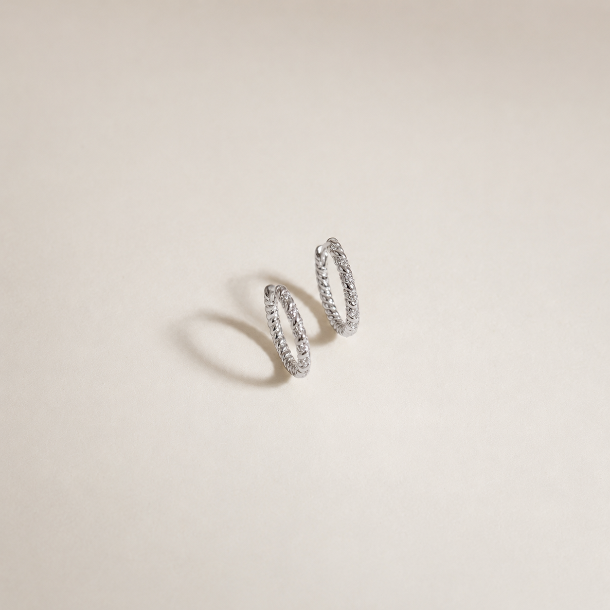 Pair of silver hoop earrings on a beige background