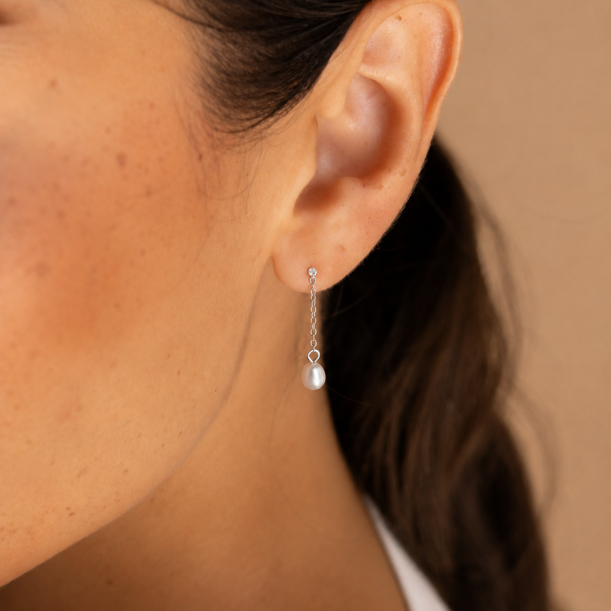 Close-up of an ear wearing a pearl earring with a blurred background