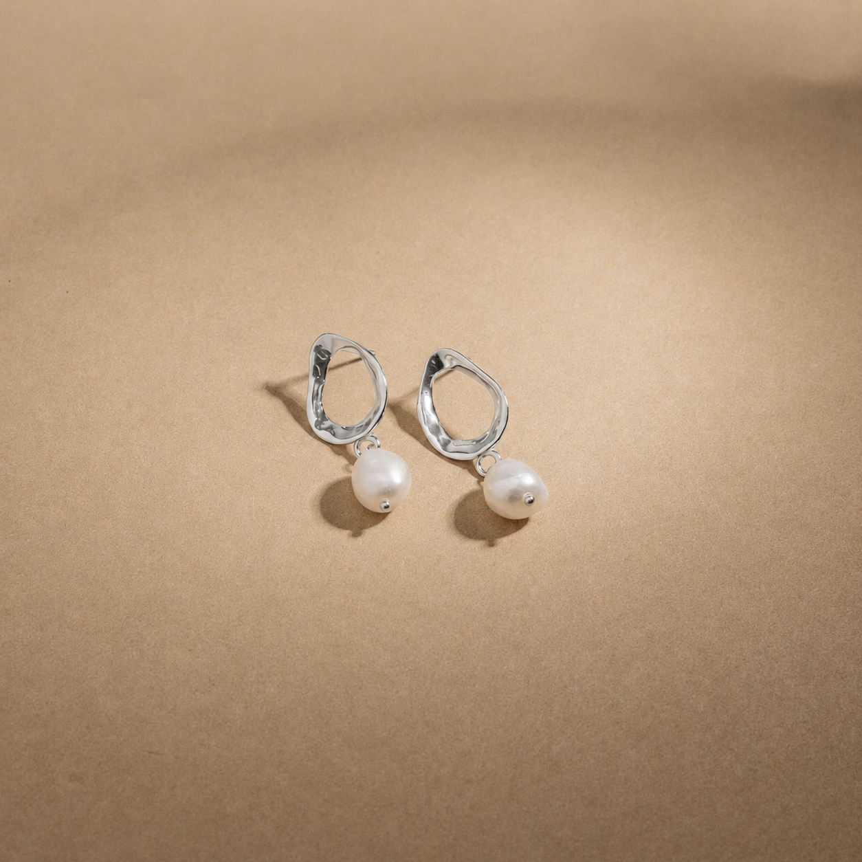 Pair of pearl earrings on a beige background