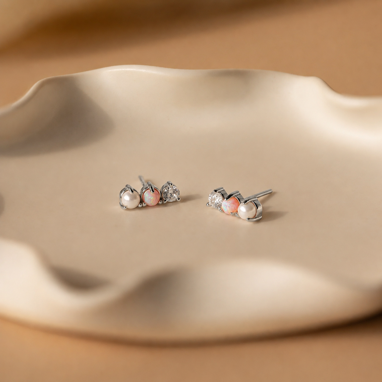 Pair of pearl stud earrings on a beige ceramic dish