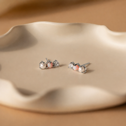 Pair of pearl stud earrings on a beige ceramic dish