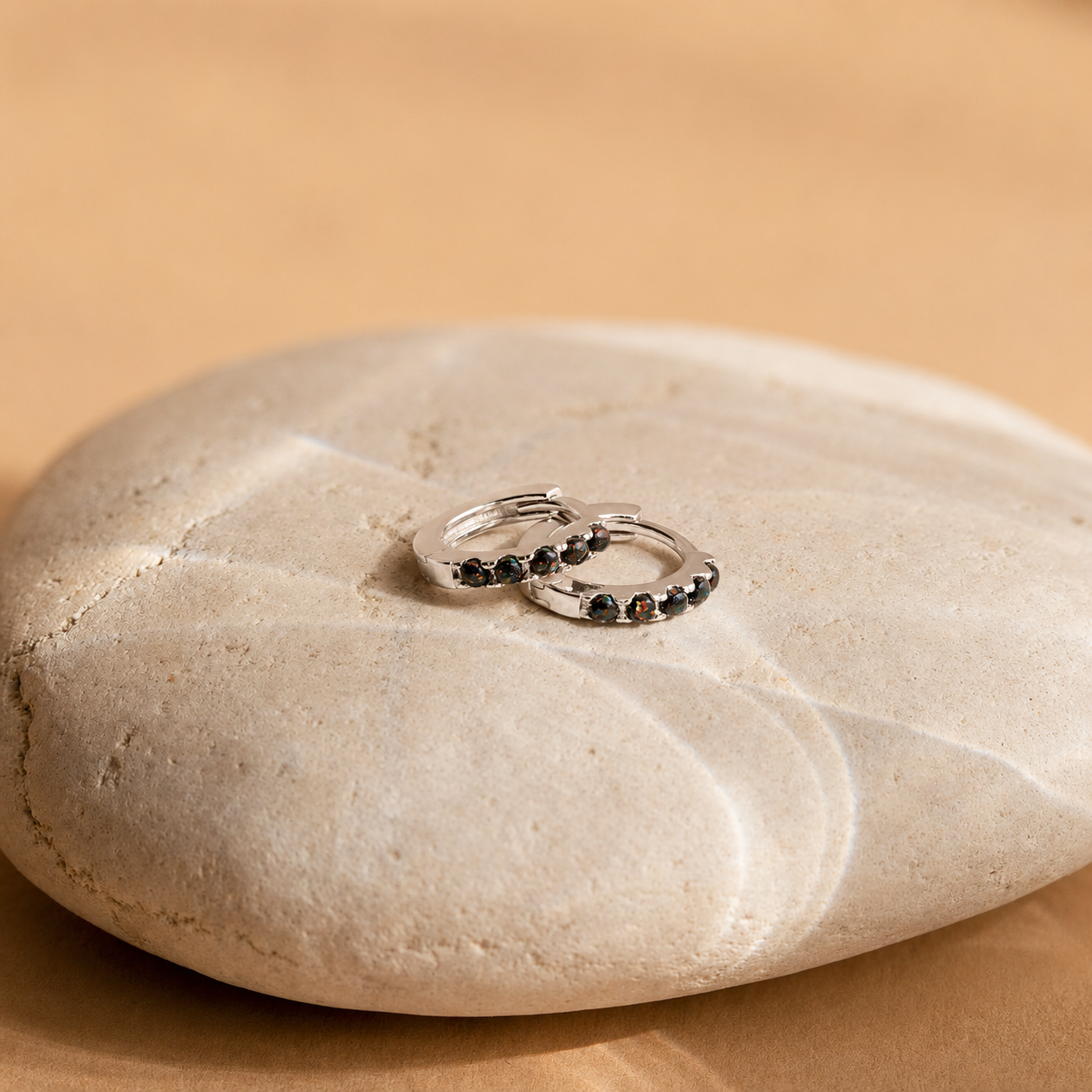 Two silver rings with black stones on a beige stone surface