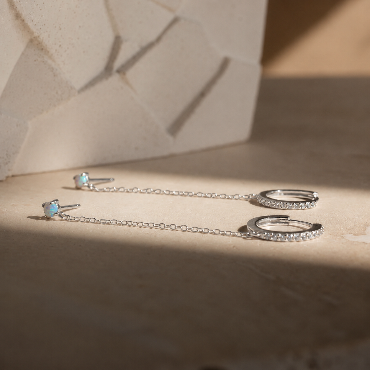 Silver earrings with gemstones on a textured surface
