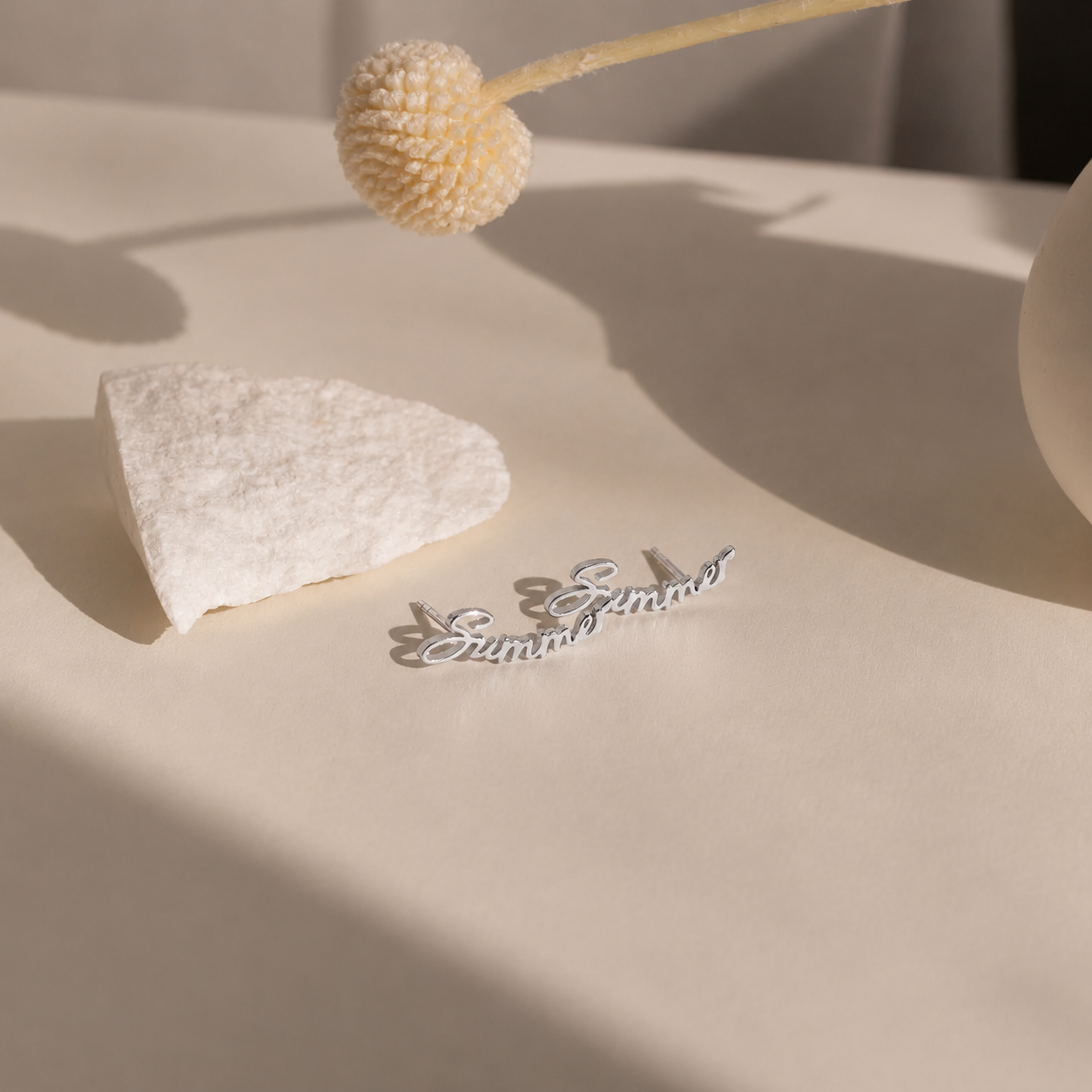Silver ring with 'E & J' engraving on a textured beige surface with a dried flower.