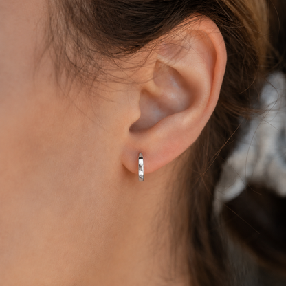 Close-up of an ear wearing a gold hoop earring with blurred background