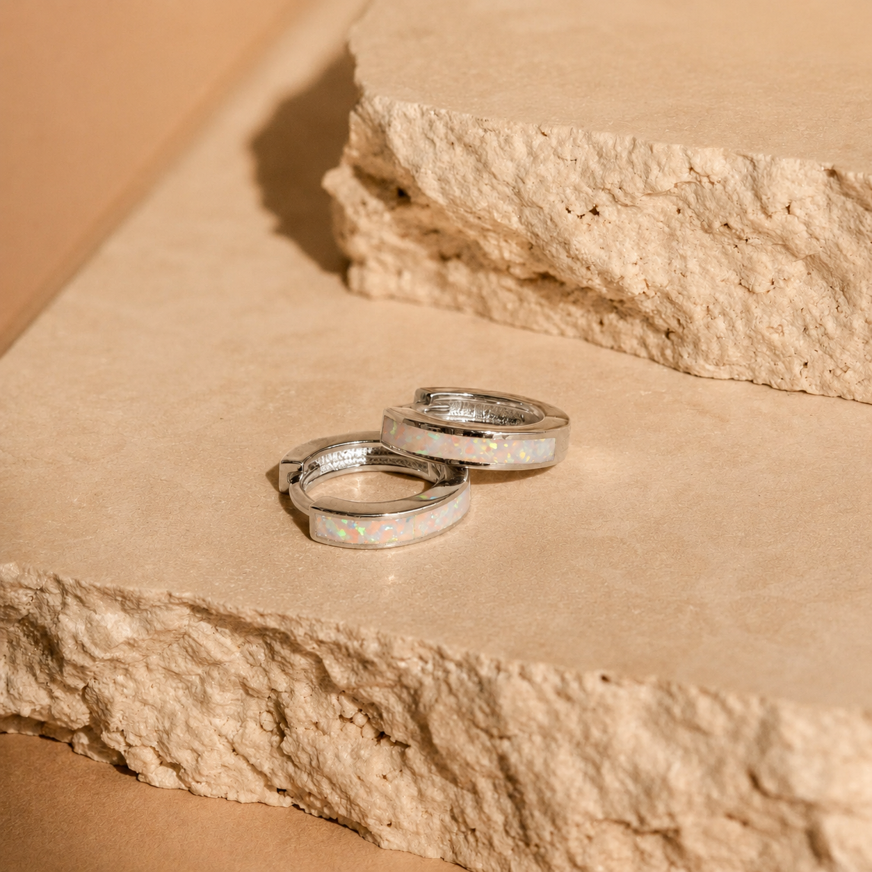Two silver rings with opal inlay on a stone surface