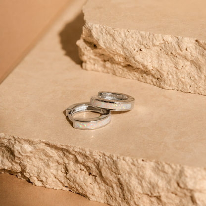 Two silver rings with opal inlay on a stone surface