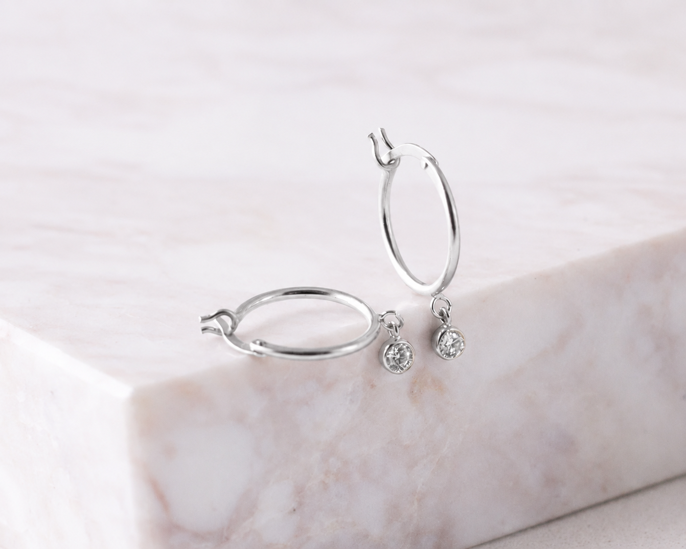 Silver hoop earrings with small round earrings on a marble surface
