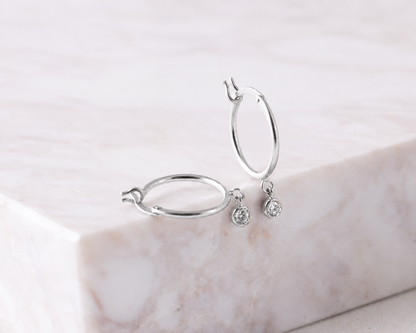 Silver hoop earrings with small round earrings on a marble surface