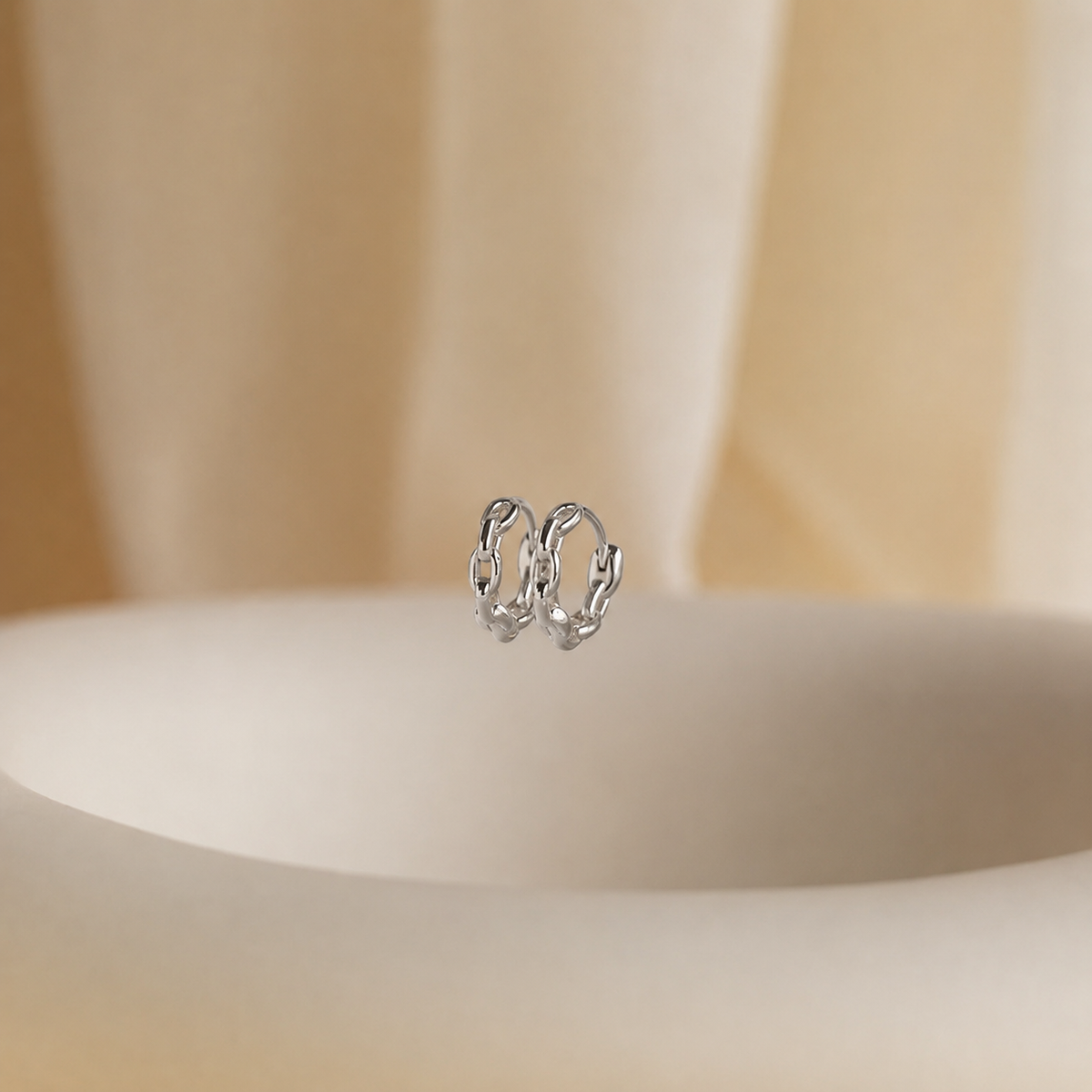 Pair of silver hoop earrings on a beige background
