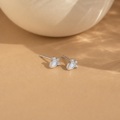 Pair of silver earrings with gemstones on a beige surface
