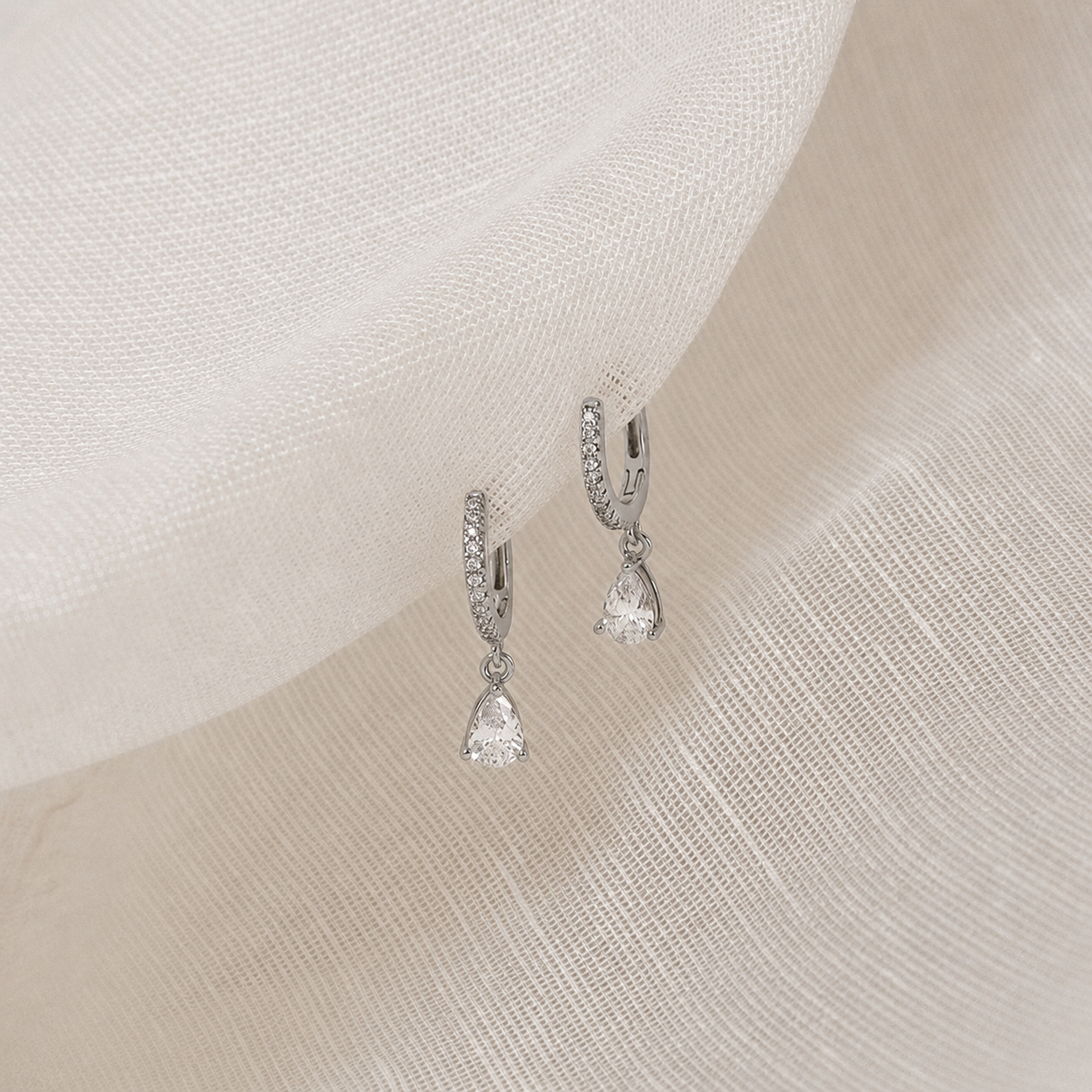 Pair of silver earrings on a soft fabric background