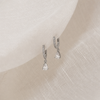 Pair of silver earrings on a soft fabric background