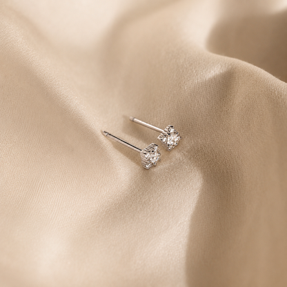Pair of silver earrings on a beige fabric background