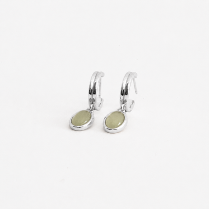 Silver hoop earrings with green stones on a white background