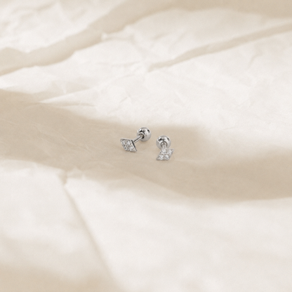 Pair of silver earrings on a soft beige fabric background