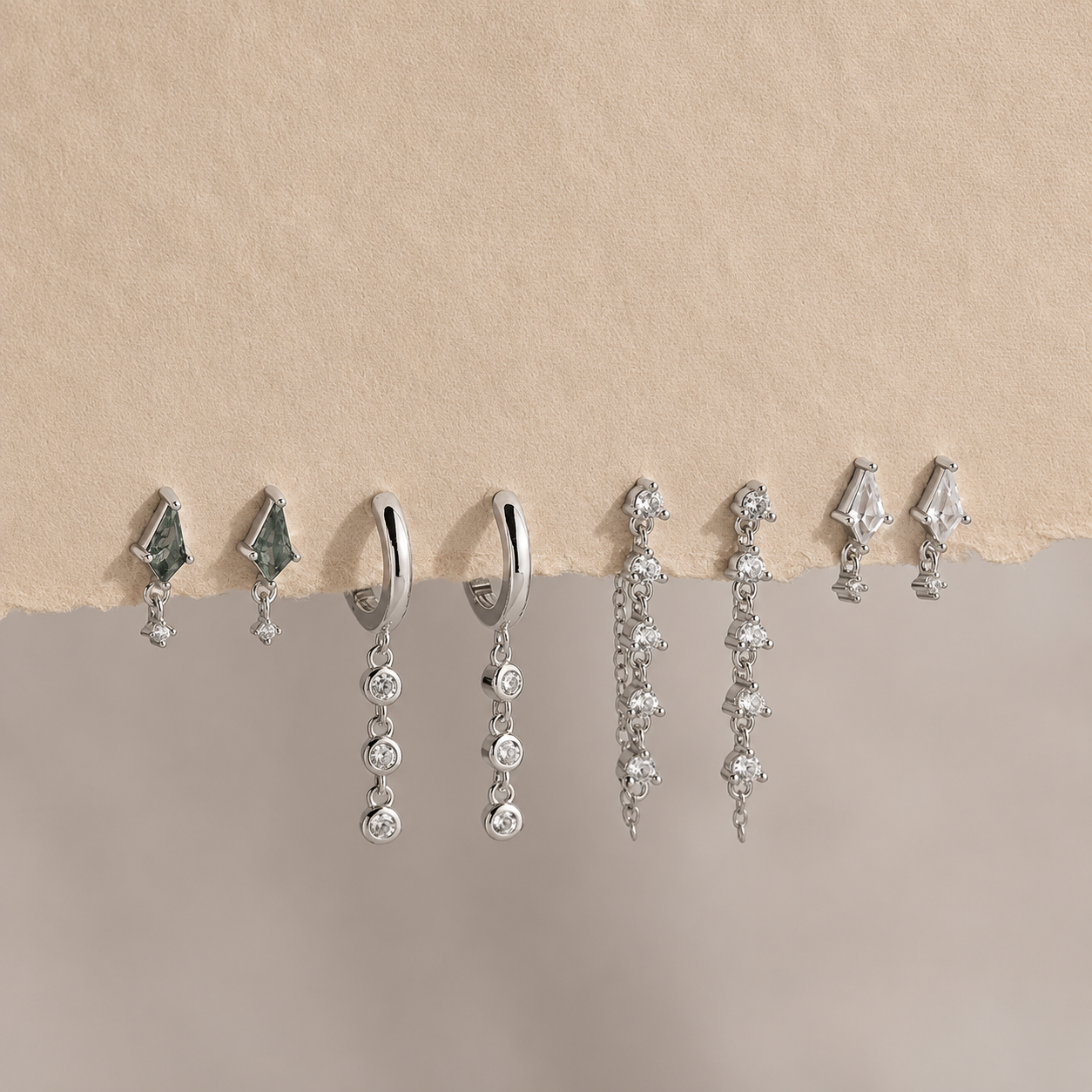 Collection of silver earrings on a beige background