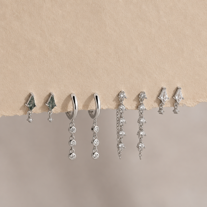 Collection of silver earrings on a beige background