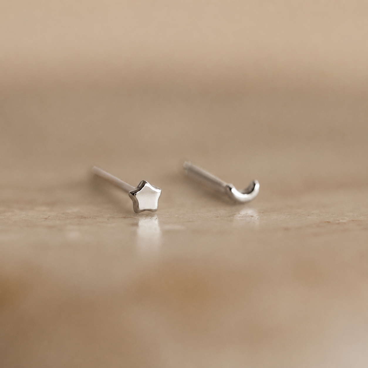 Silver star-shaped earrings on a beige background
